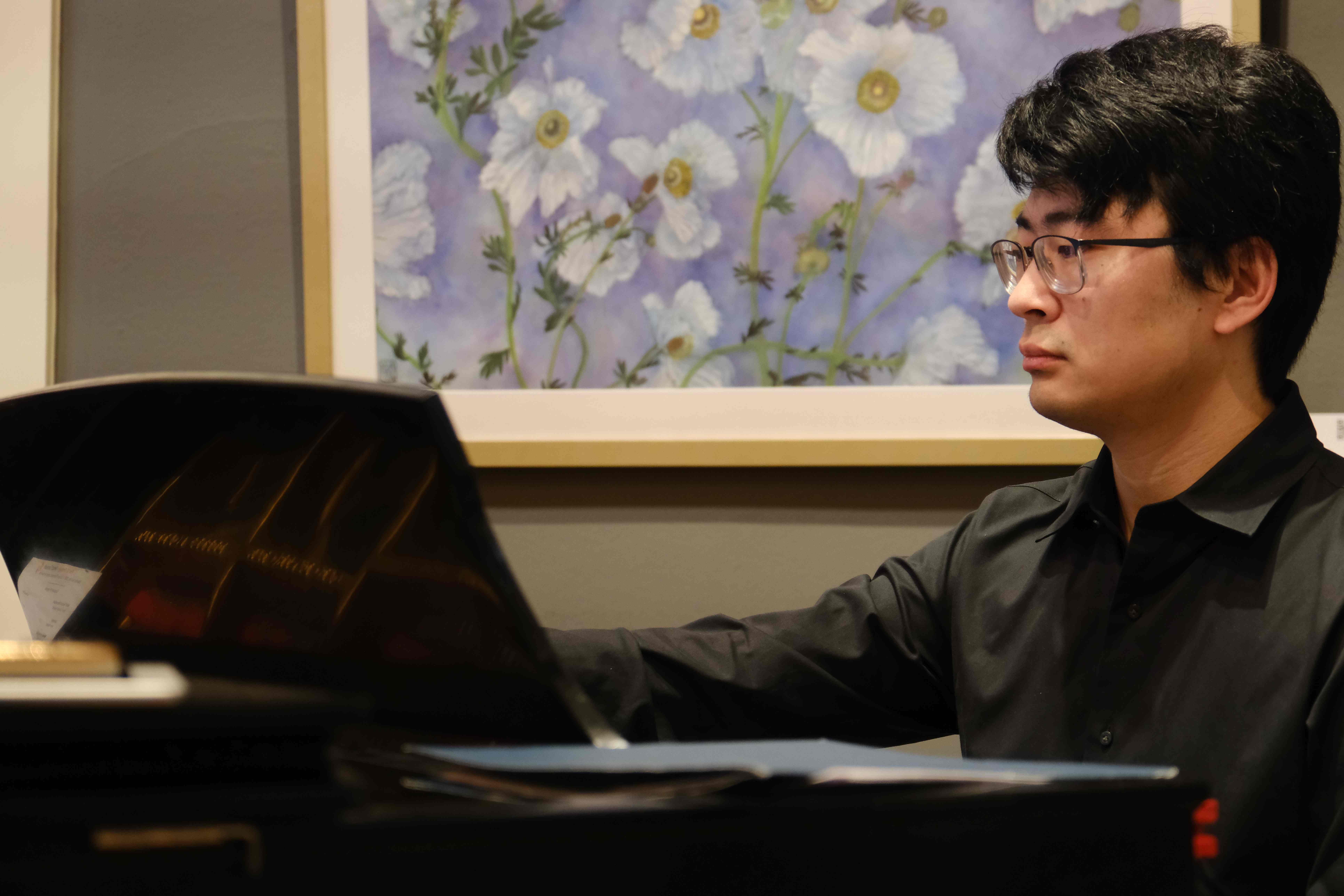 Pianist performing with floral artwork in background