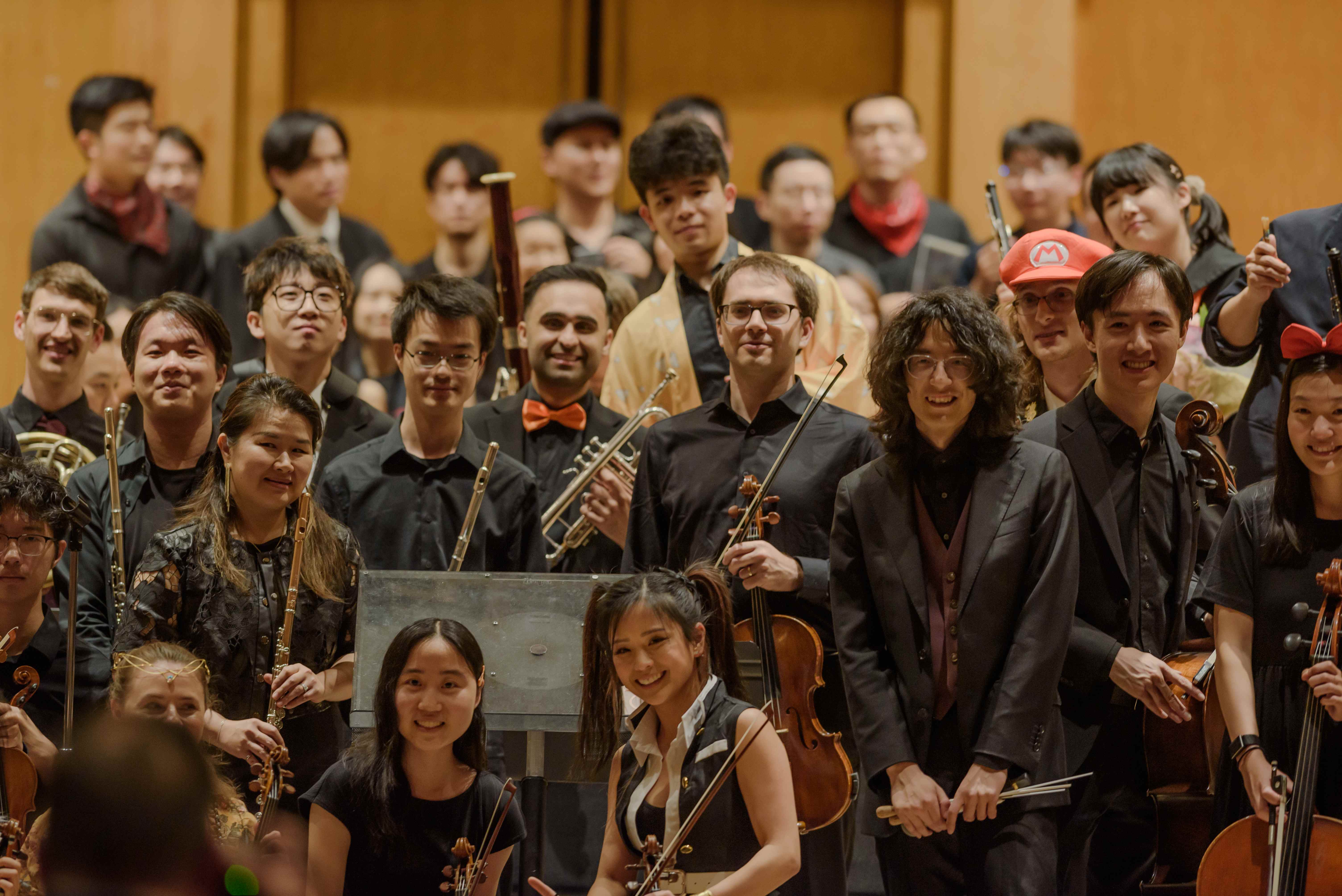 The GG Orchestra musicians smiling together on stage with their instruments