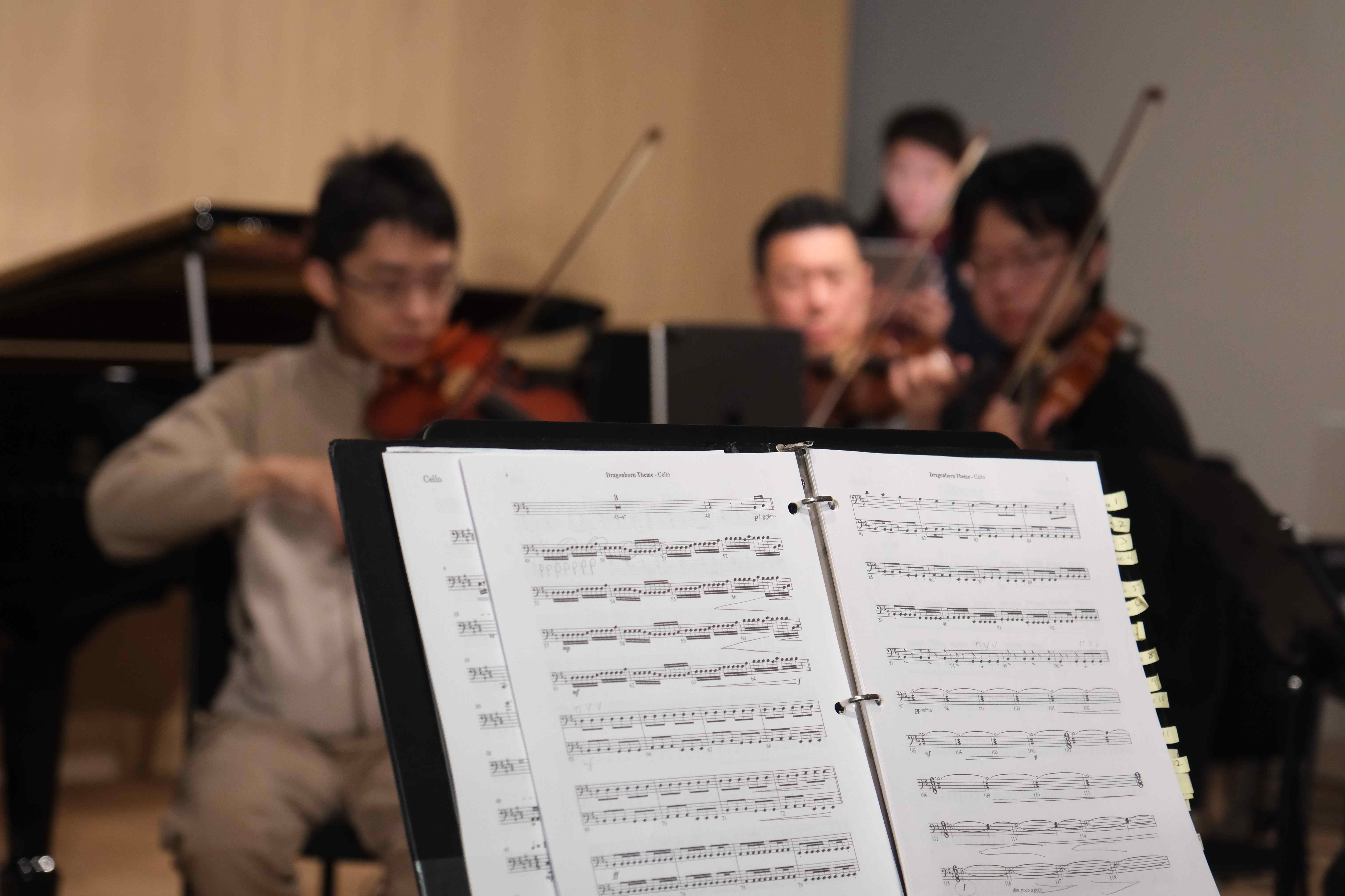 Sheet music on stand with violinists rehearsing in background